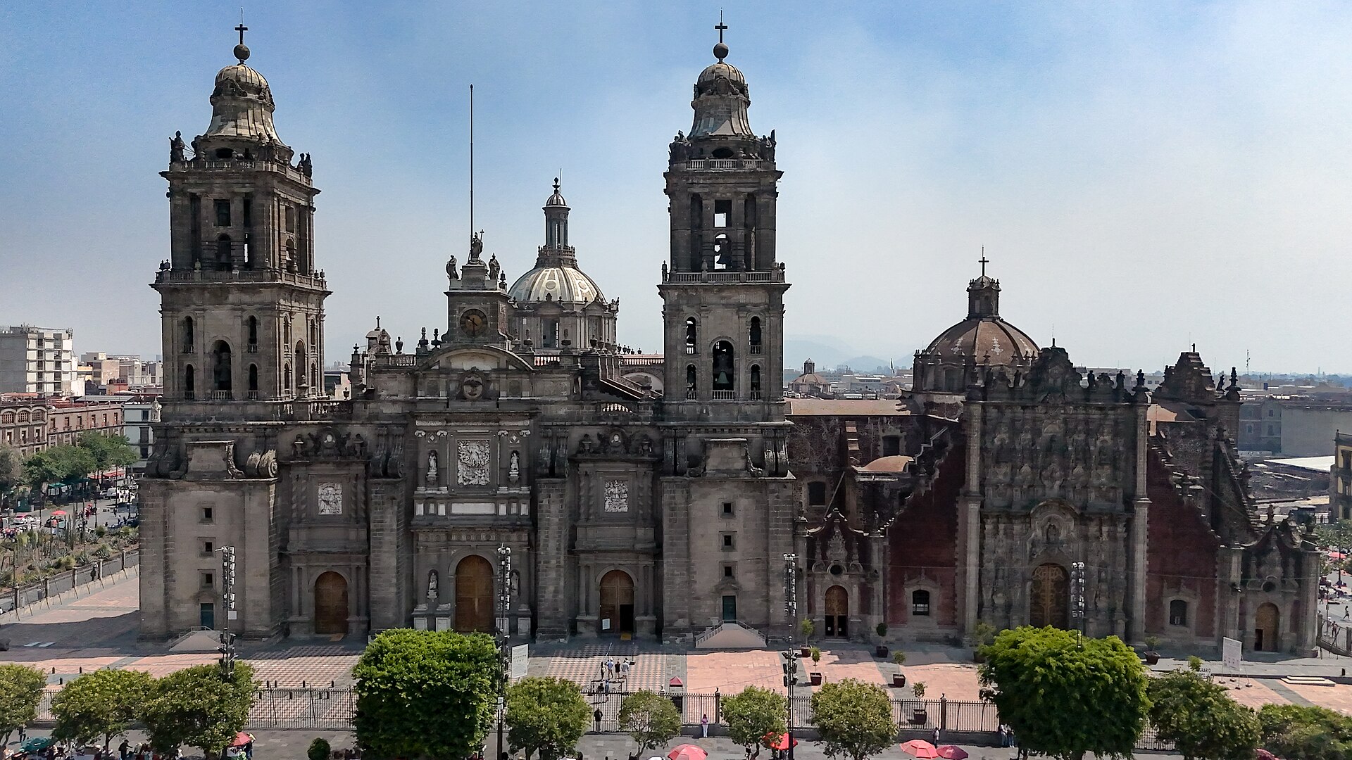 Metropolitan Cathedral of Mexico City with its baroque facade, domes, and bell towers under a clear sky. The imposing stone structure domina